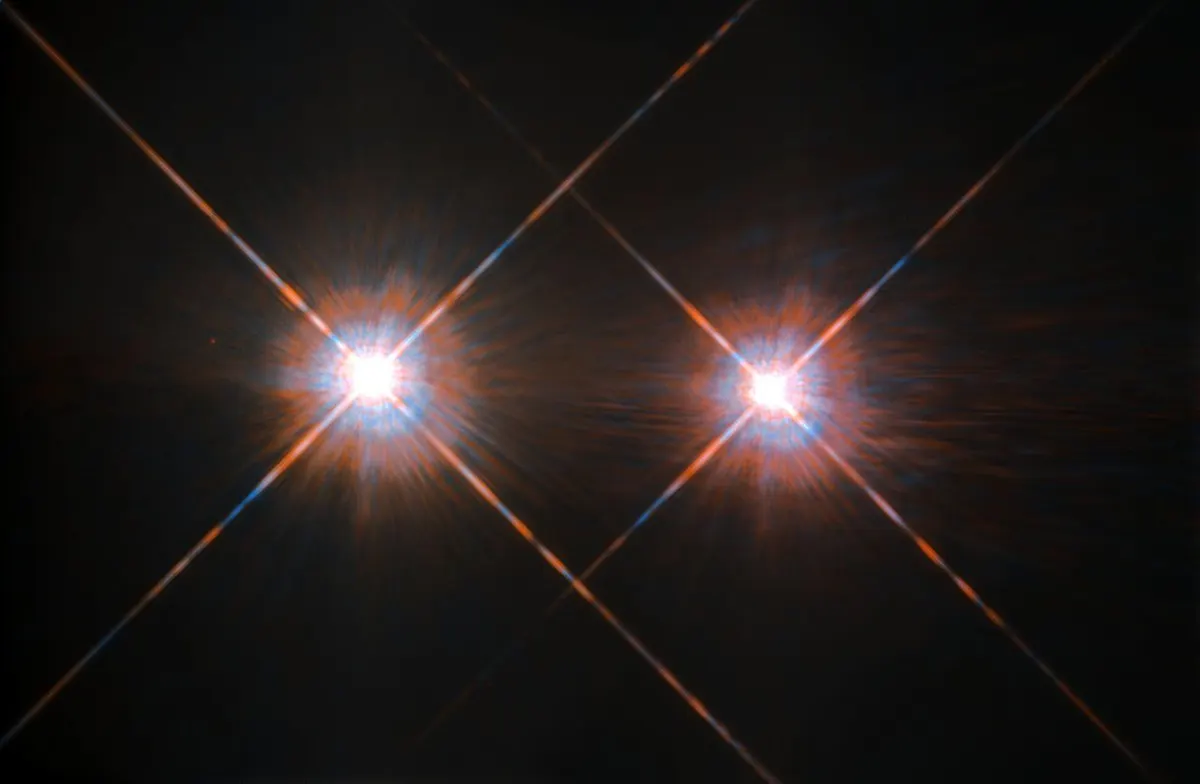 Two bright blue-white stars with diffraction spikes against black space