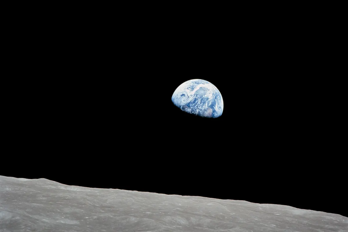 The blue and white Earth above the gray horizon of the Moon against black space