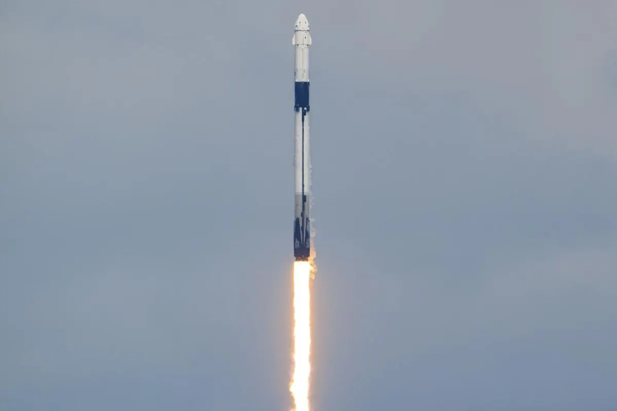 A Falcon 9 rocket with a Dragon spacecraft climbing into a pale sky