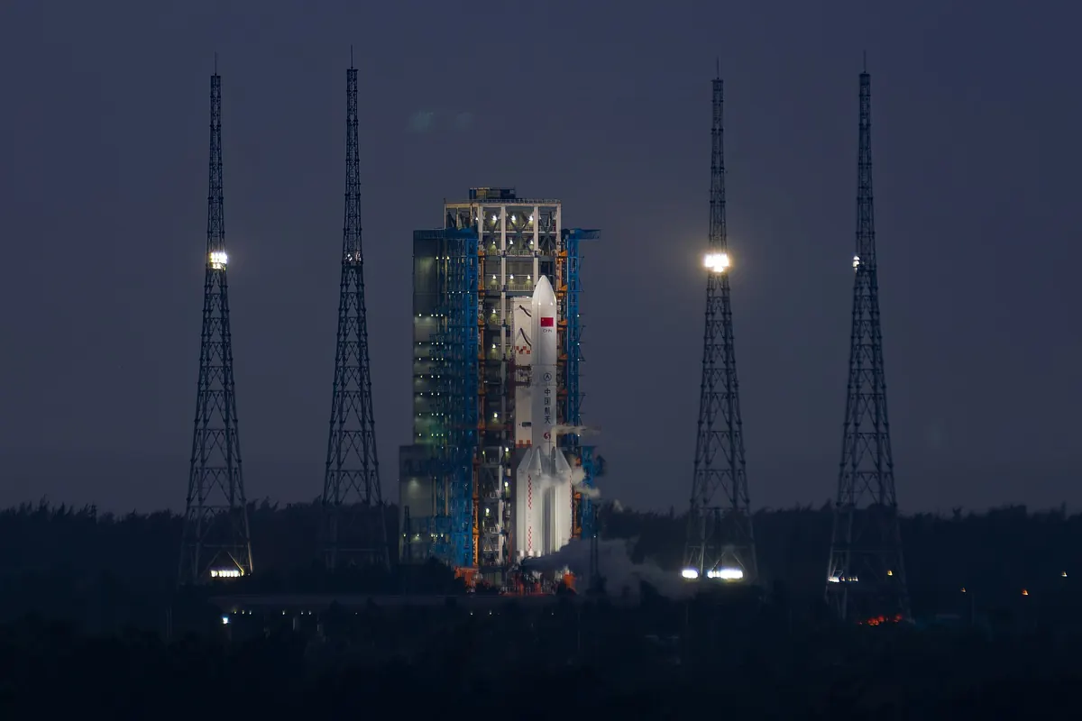 A Long March 5 rocket on its launch pad at night, between four lightning towers