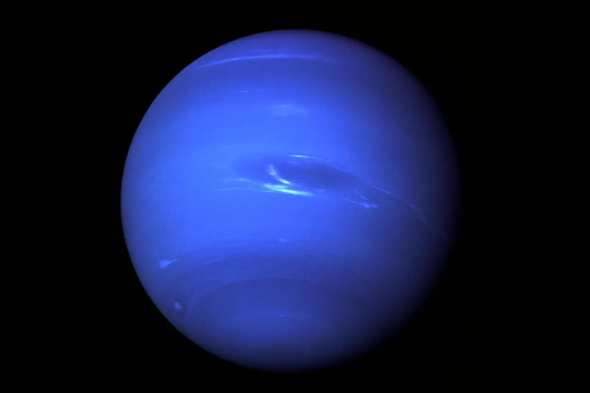 Neptune as a deep blue disk with a dark oval storm and white clouds