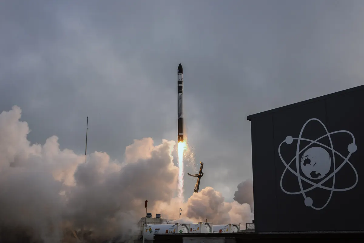 A Rocket Lab Electron rocket climbing on a plume of flame and smoke from its launch pad in New Zealand