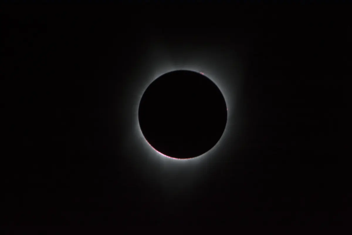 The black disc of the Moon covering the Sun, with the white corona streaming out around it