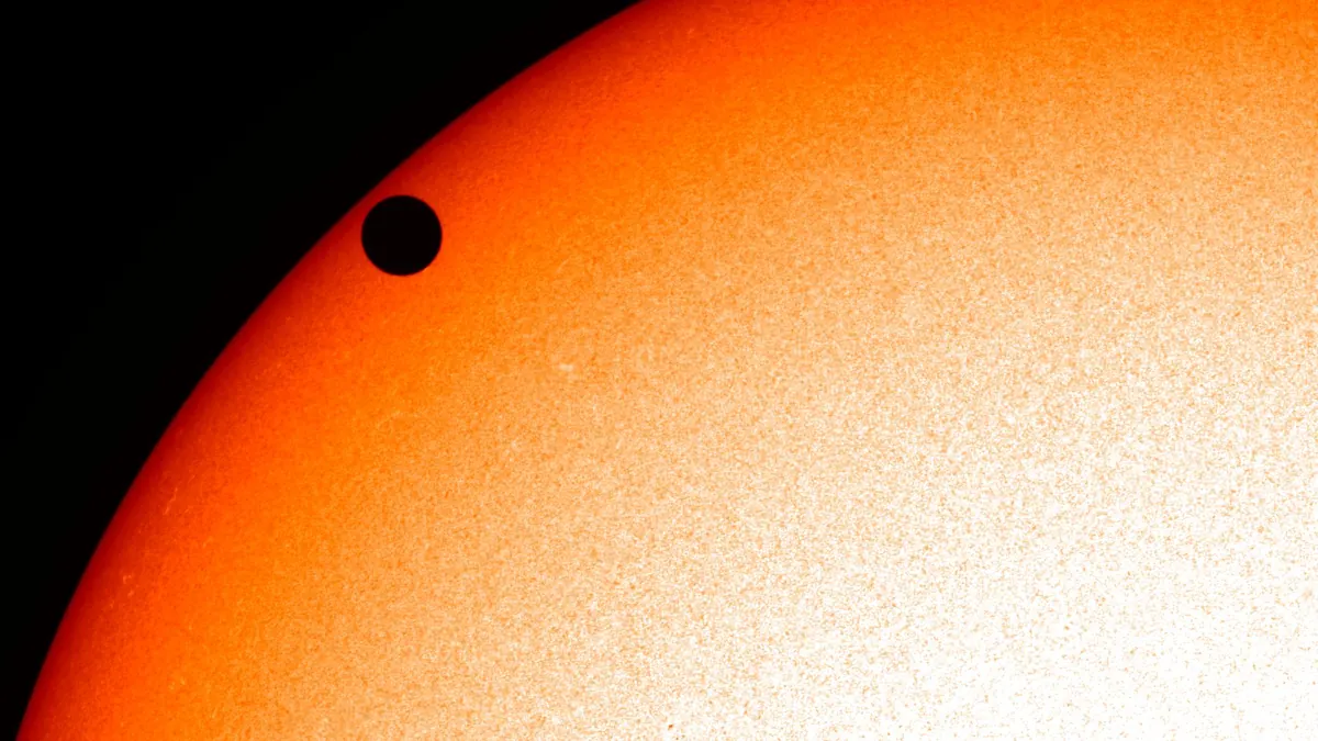 The Sun's glowing disc with the round black shadow of Venus crossing its edge